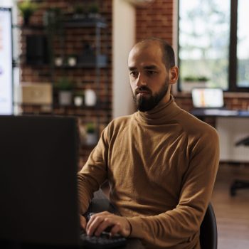 Development agency office worker analyzing project sales and fintech startup. Businessperson sitting at desk in marketing company office developing financial strategy and accounting management.